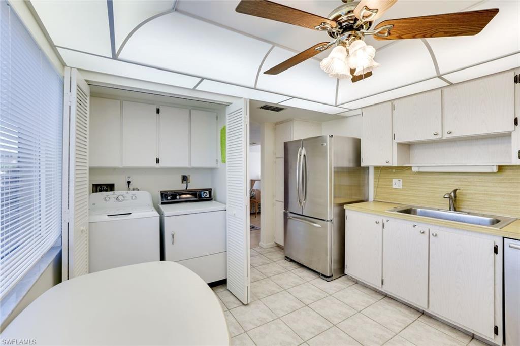 247 Winners Circle, Unit 5 Naples, FL 34112 - Photo 7 of 24 Kitchen featuring light countertops, freestanding refrigerator, white cabinetry, separate washer and dryer, and a ceiling fan