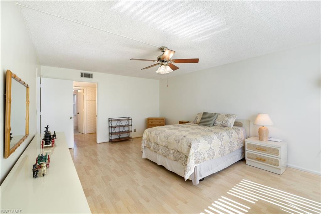 247 Winners Circle, Unit 5 Naples, FL 34112 - Photo 10 of 24 Bedroom featuring light wood finished floors, a textured ceiling, and a ceiling fan