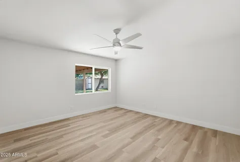 an empty room with a window and a ceiling fan
