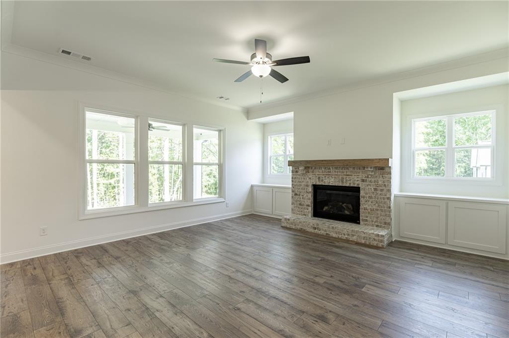 1210 Austin Road Winder, GA 30680 - Photo 23 of 56 an empty room with windows a fireplace and wooden floor