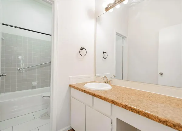 a bathroom with a granite countertop sink and a mirror a bathtub