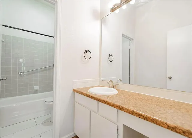 a bathroom with a granite countertop sink and a mirror a bathtub