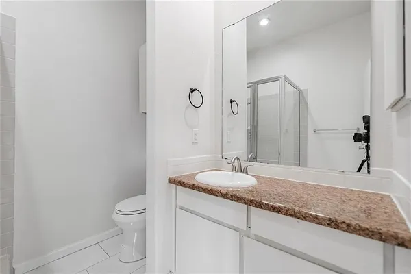 a bathroom with a granite countertop sink a toilet and a mirror