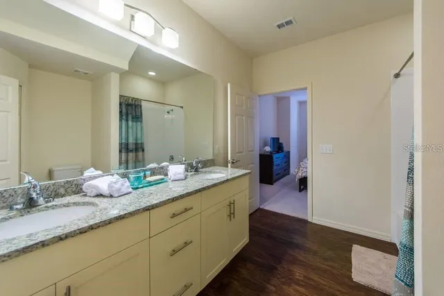 a en suite bathroom with a granite countertop double vanity sink and mirror