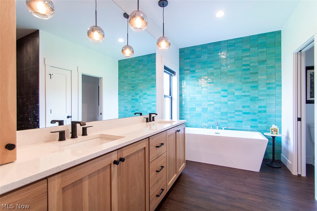 4197 Beach Road Medina, OH 44256 - Photo 22 of 35 Bathroom featuring tile walls, large vanity, a bathtub, wood-type flooring, and dual sinks