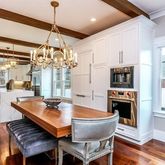 a dining room with stainless steel appliances kitchen island granite countertop a table chairs and a chandelier