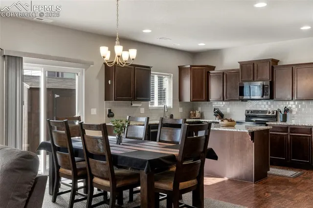 a kitchen with stainless steel appliances granite countertop a sink a stove a dining table and chairs