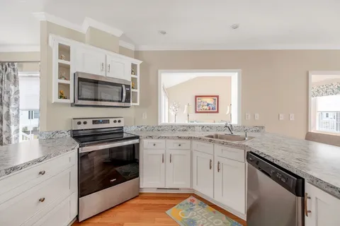 a kitchen with granite countertop stainless steel appliances a stove microwave and sink