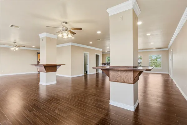 a view of an empty room with wooden floor and a kitchen