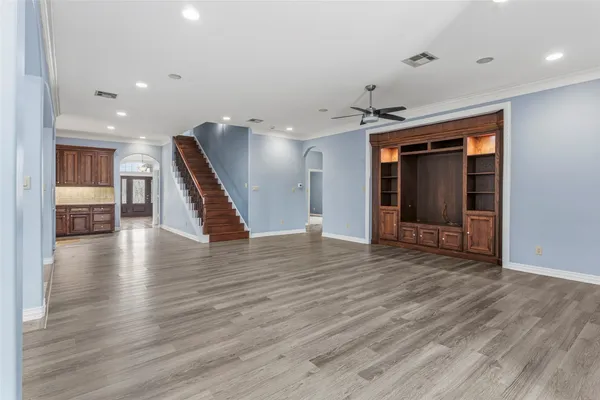 a view of a hallway with wooden floor and a kitchen space