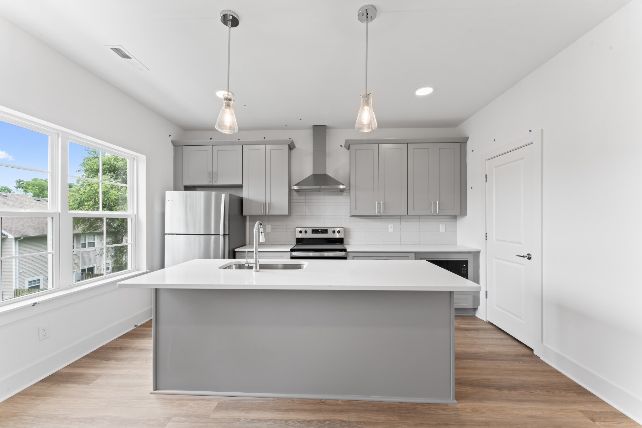 a large kitchen with stainless steel appliances kitchen island a large counter top a sink cabinets and a wooden floor