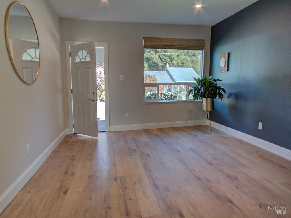 1002 Cedar Street Fort Bragg, CA 95437 - Photo 7 of 26 an empty room with wooden floor mirror and windows