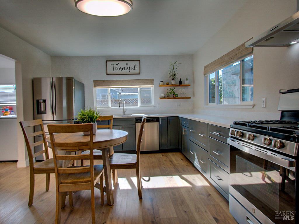 1002 Cedar Street Fort Bragg, CA 95437 - Photo 8 of 26 a kitchen with stainless steel appliances a stove a sink dishwasher and a dining table with wooden floor