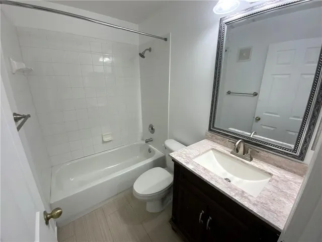 a bathroom with a granite countertop sink a toilet a mirror and shower