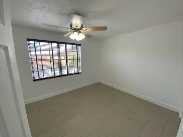 en empty room with windows and chandelier fan