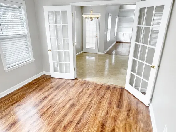 an empty room with wooden floor and windows