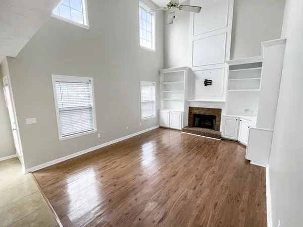 an empty room with wooden floor fireplace and windows