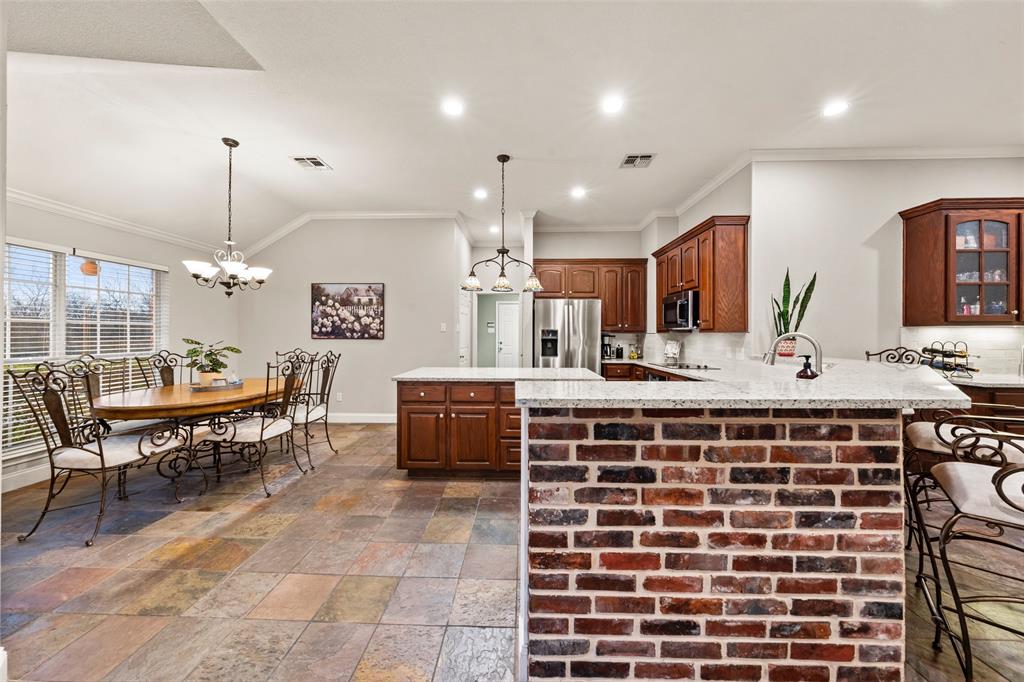 517 Chado Lane Robinson, TX 76706 - Photo 11 of 40 Dining space attached to kithchen with stone tile flooring, hanging lights, healthy amount of natural light, ornamental molding, and vaulted ceiling