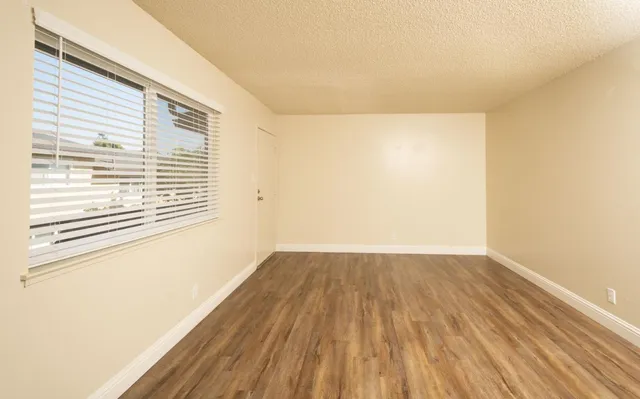 a view of an empty room with wooden floor and a window