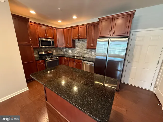 a kitchen with stainless steel appliances granite countertop a sink refrigerator and microwave