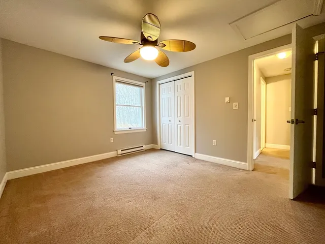 an empty room with a chandelier fan and windows