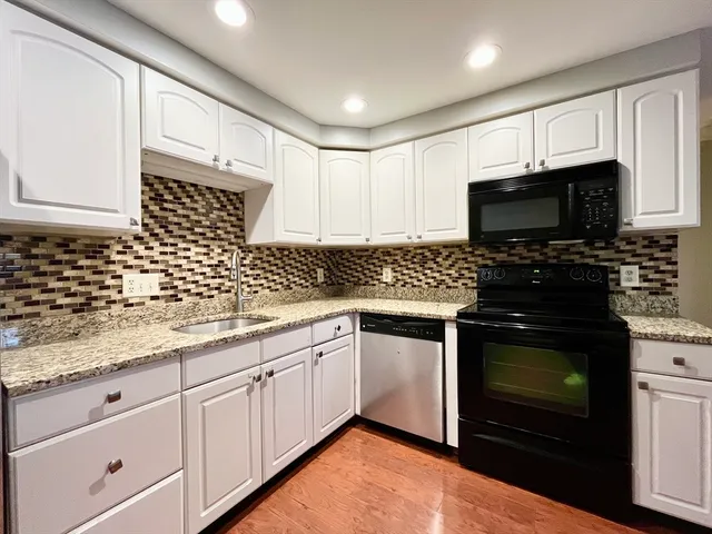 a kitchen with granite countertop a sink a stove and cabinets