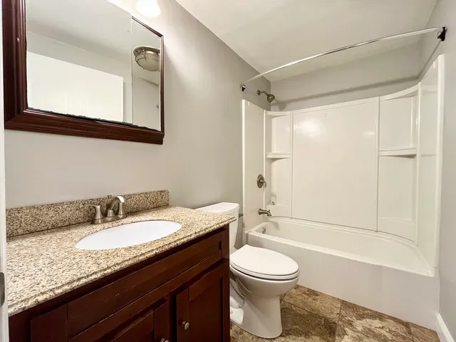 a bathroom with a granite countertop sink toilet a mirror and a bathtub