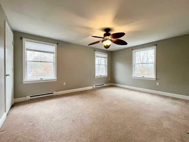 a view of an empty room with windows and ceiling fan
