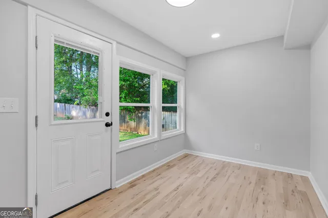 a view of an empty room with wooden floor and a window