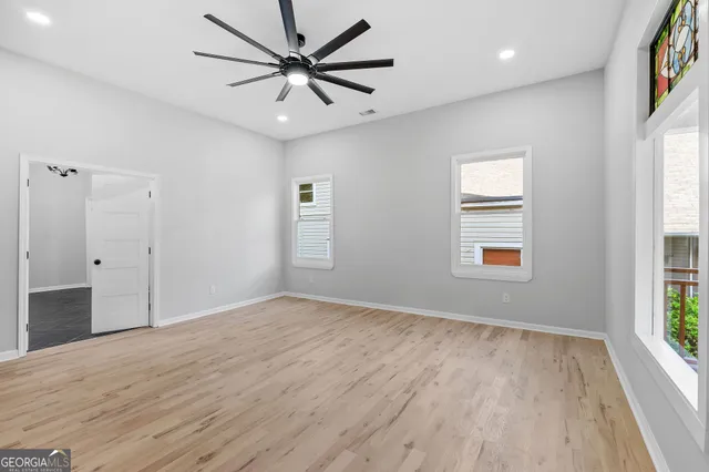 an empty room with wooden floor and windows