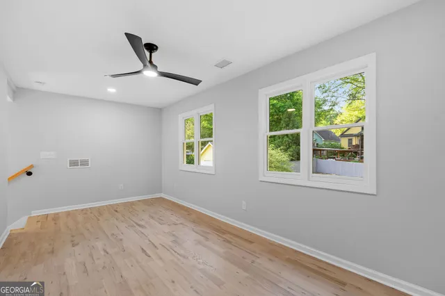 a view of empty room with wooden floor and fan