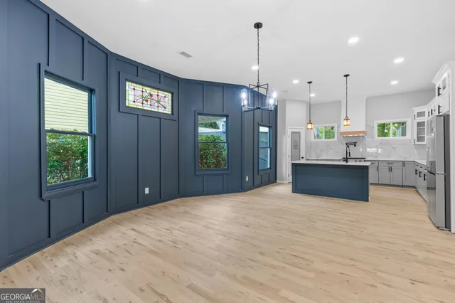 a kitchen with stainless steel appliances kitchen island granite countertop a refrigerator a sink dishwasher and a fireplace with wooden floor