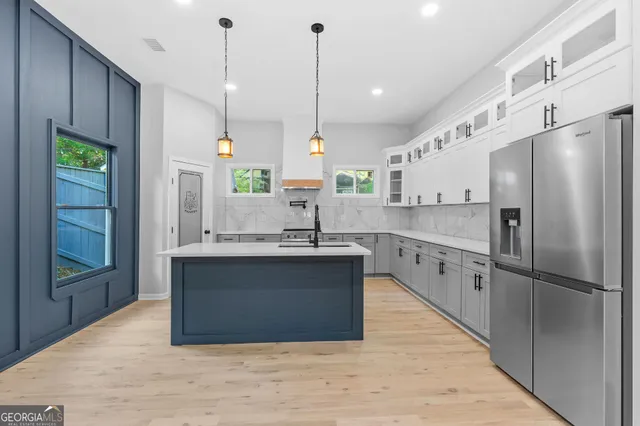 a kitchen with stainless steel appliances granite countertop a sink a refrigerator a stove and a wooden floors