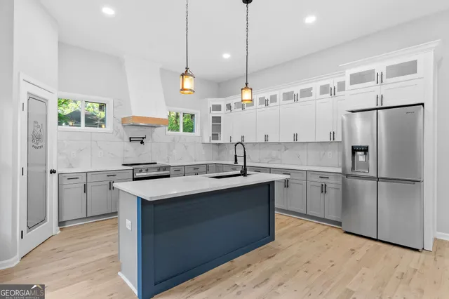 a kitchen with stainless steel appliances granite countertop a sink a stove a refrigerator and island with wooden floor