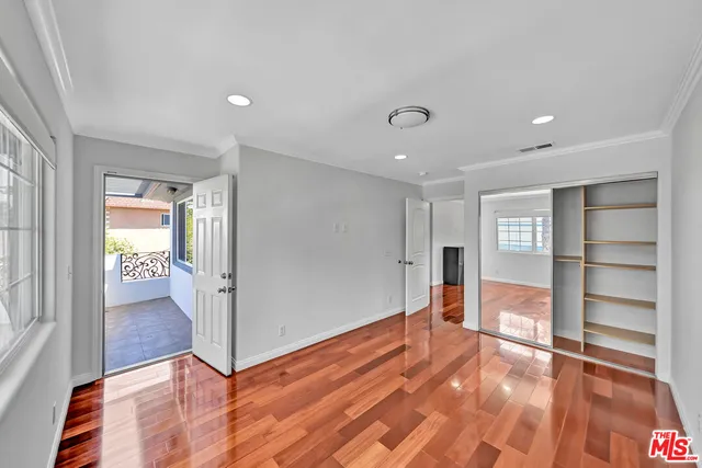 a view of empty room with wooden floor and window