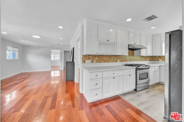 a open kitchen with white cabinets and stainless steel appliances