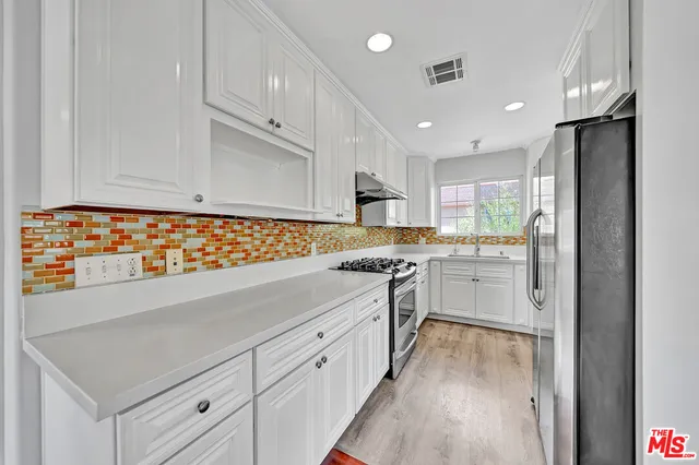 a kitchen with white cabinets and appliances