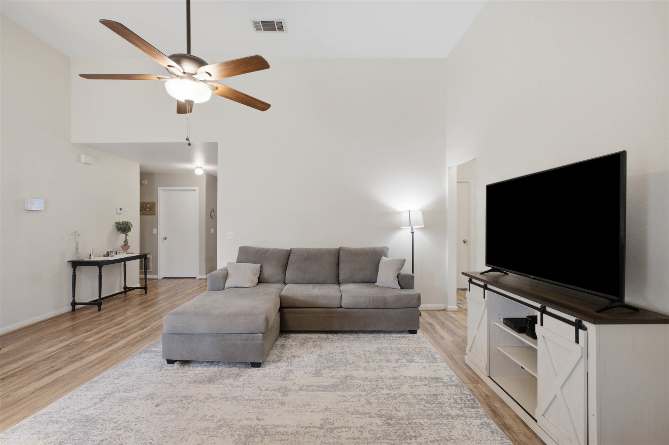 1717 Rendova Lane Pflugerville, TX 78660 - Photo 10 of 32 A comfortable living space featuring vaulted ceilings and warm wood flooring.