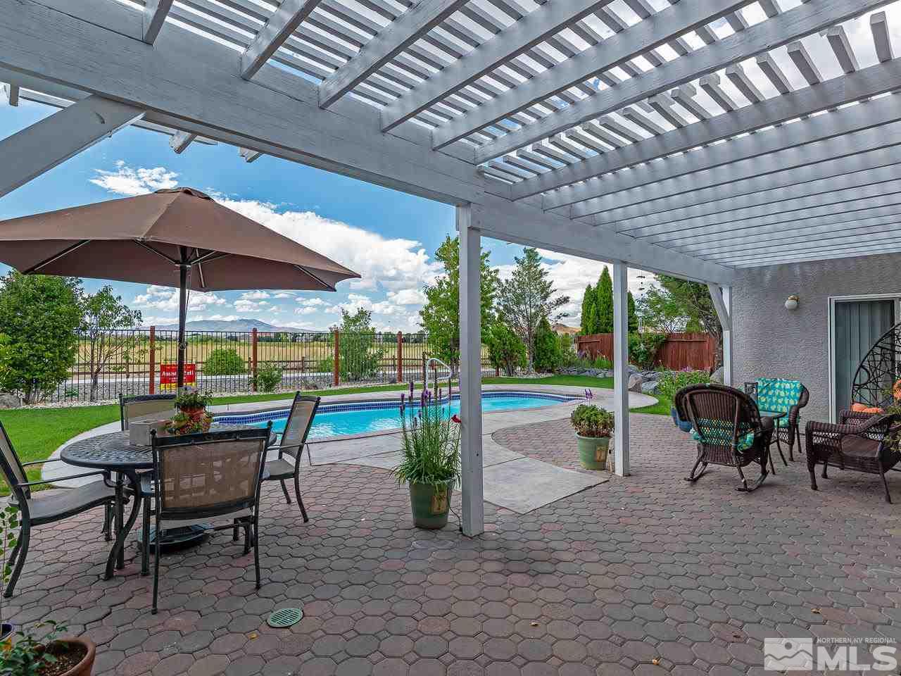 10675 Silver Cliff Way Reno, NV 89521 - Photo 2 of 16 a view of a patio with a dining table and chairs under an umbrella with a barbeque grill