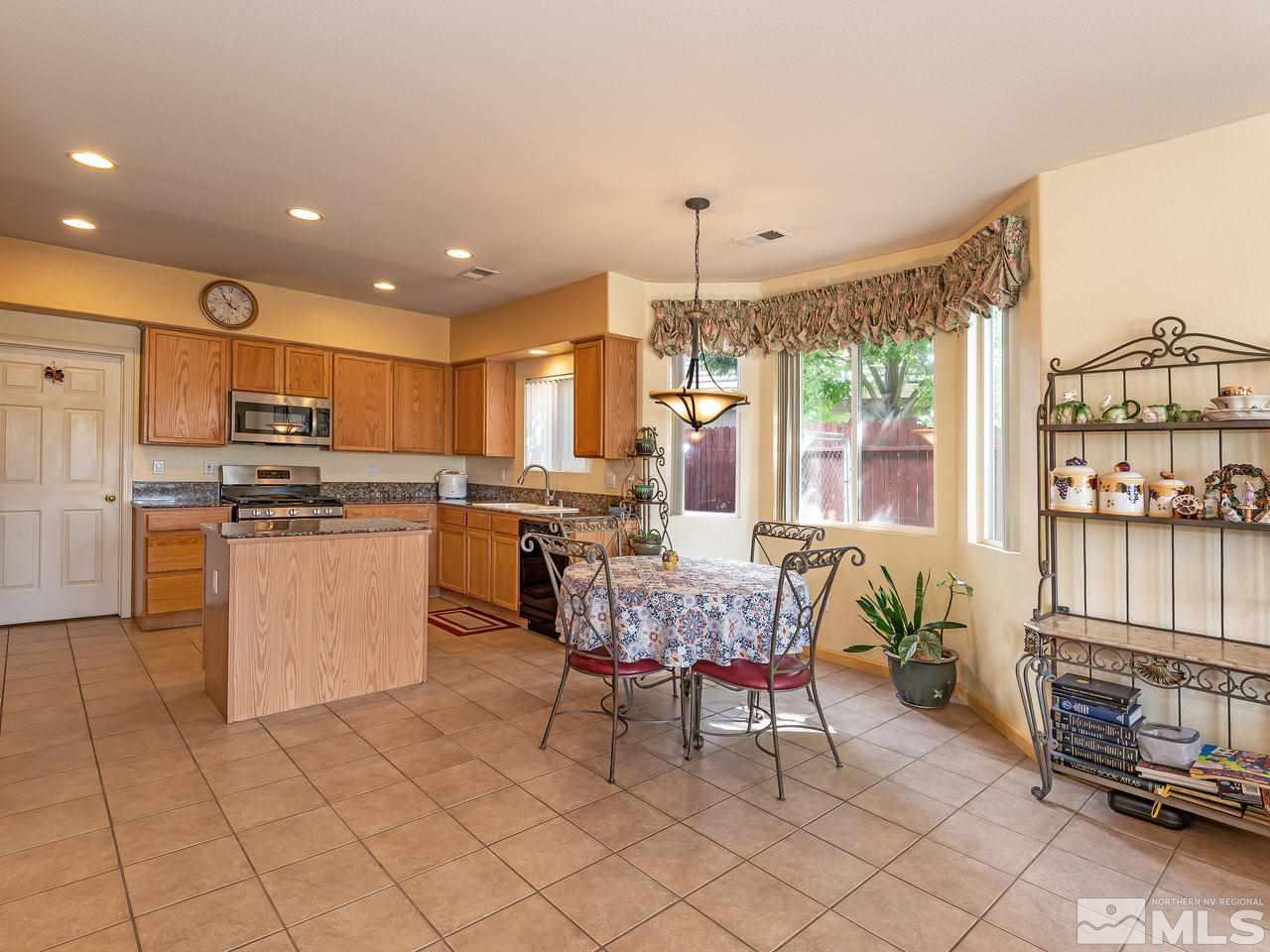 10675 Silver Cliff Way Reno, NV 89521 - Photo 7 of 16 a kitchen with stainless steel appliances kitchen island granite countertop a refrigerator and cabinets