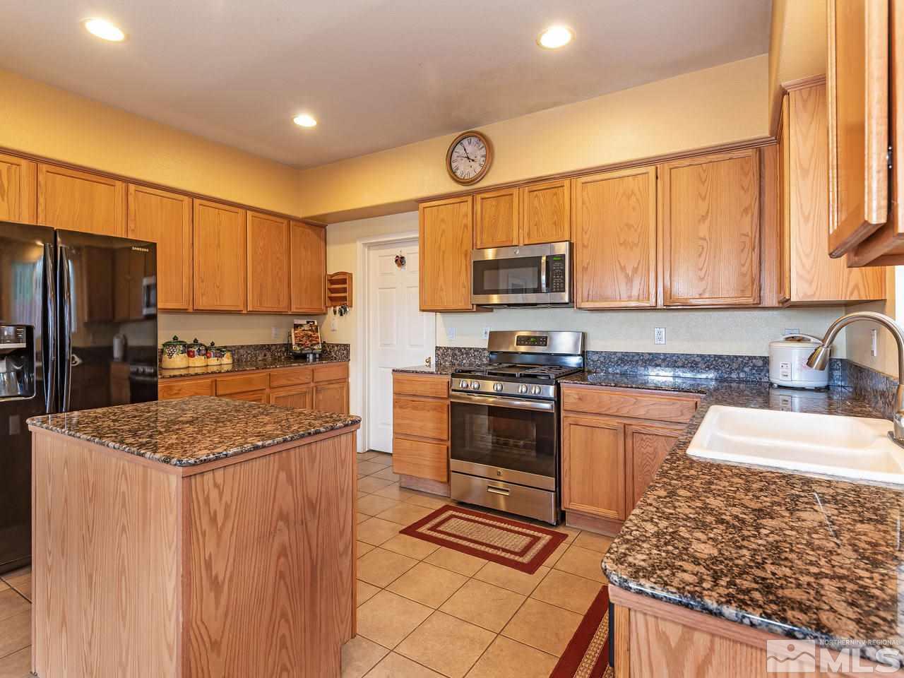 10675 Silver Cliff Way Reno, NV 89521 - Photo 8 of 16 a kitchen with stainless steel appliances kitchen island granite countertop a stove refrigerator and microwave