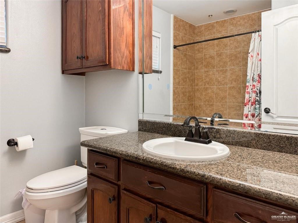 120 South Retama Lane Weslaco, TX 78596 - Photo 10 of 19 a bathroom with a granite countertop sink a toilet and a mirror