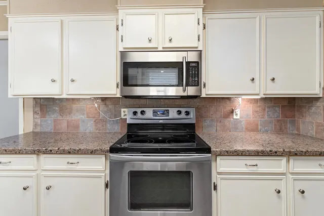 a kitchen with granite countertop white cabinets and white stove