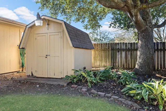 a view of a house with a yard plants and large tree