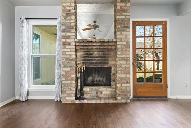 an empty room with wooden floor fire place and windows