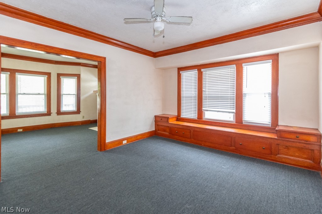 917 Helmsdale Road Cleveland Heights, OH 44112 - Photo 7 of 28 Empty room featuring dark carpet, ornamental molding, ceiling fan, and a textured ceiling