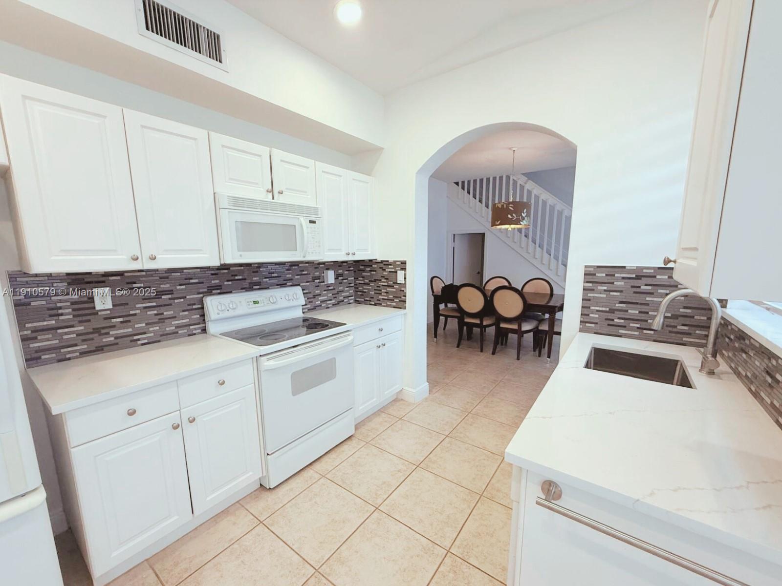 18746 Southwest 27th Court Miramar, FL 33029 - Photo 6 of 35 a kitchen with furniture a stove and white cabinets
