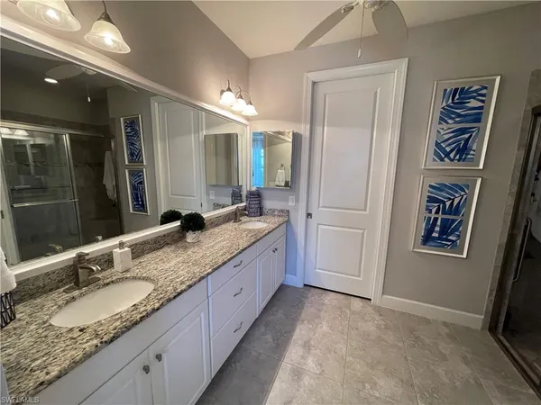 a bathroom with a granite countertop double vanity sink and a mirror