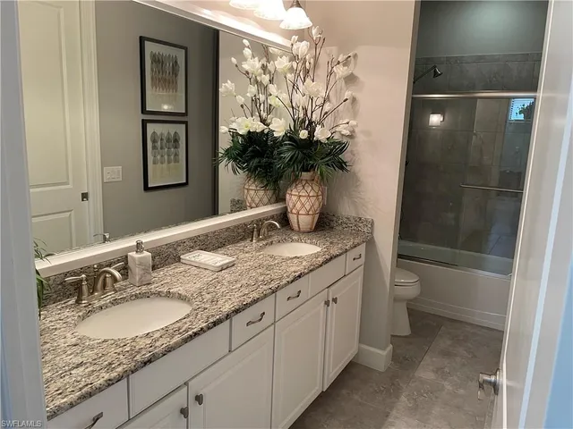 a bathroom with a granite countertop sink a toilet and shower