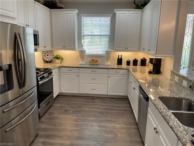 a kitchen with granite countertop stainless steel appliances a sink a stove and cabinets